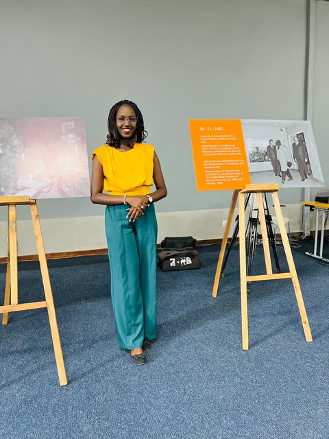 Nella standing between two exhibition boards on Burundi’s history